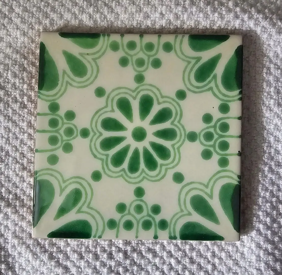 Green floral patterned tile on textured fabric.