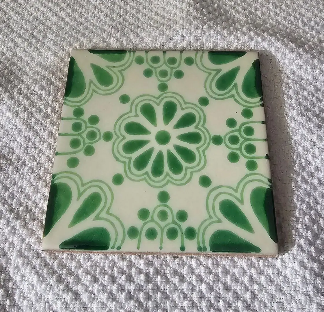 Green and white decorative tile on fabric.