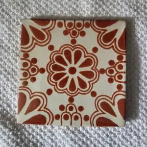Decorative ceramic tile with a red floral pattern on white background.