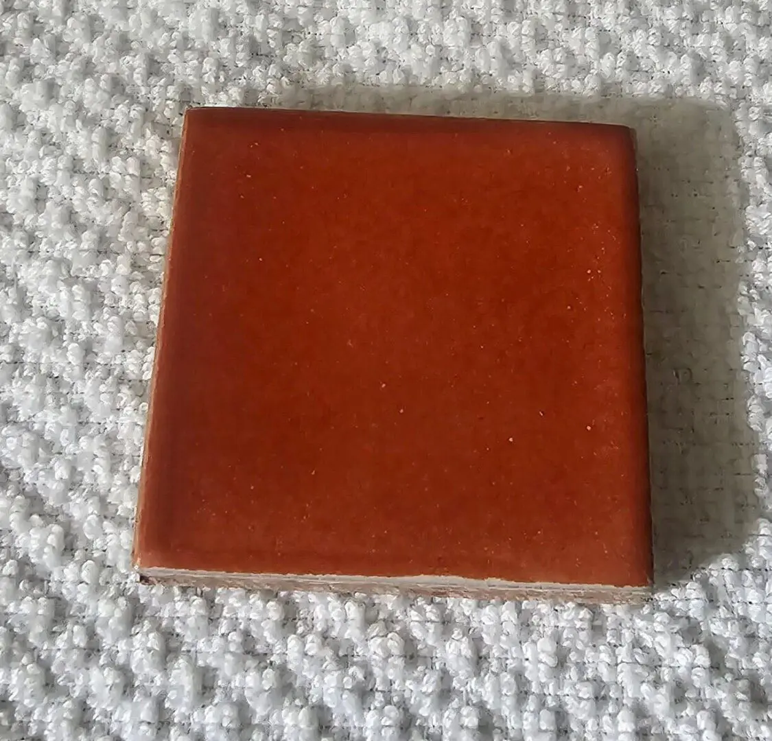 A single brown leather coaster on a textured white surface.
