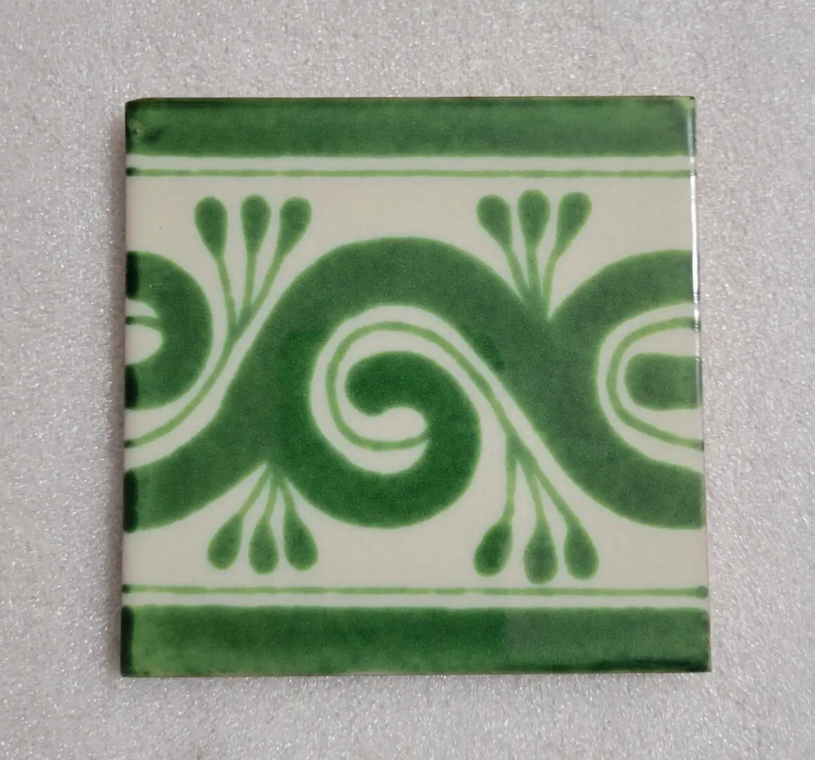 Green decorative tile with spiral pattern.