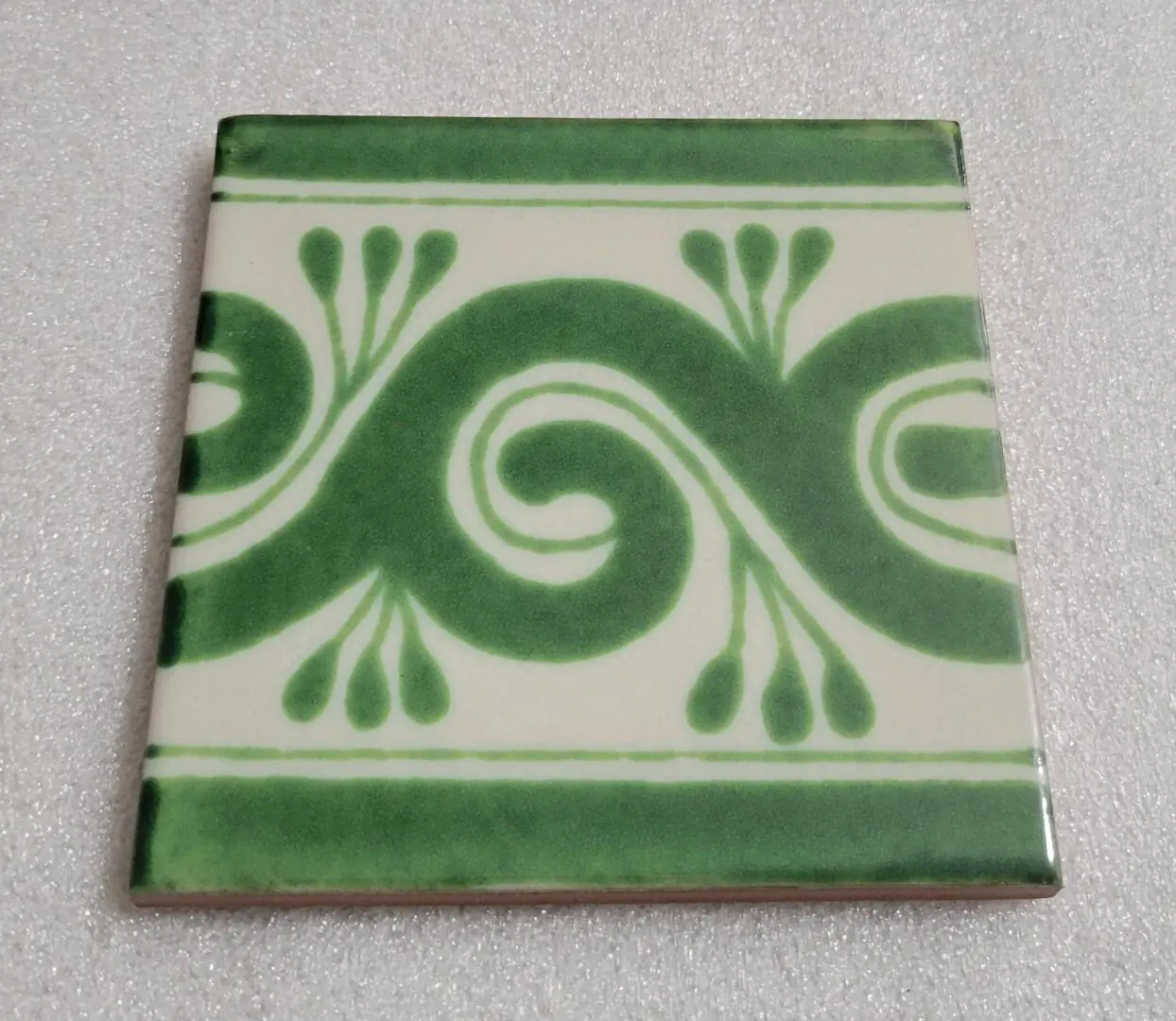 Green and white ceramic tile with swirl pattern.