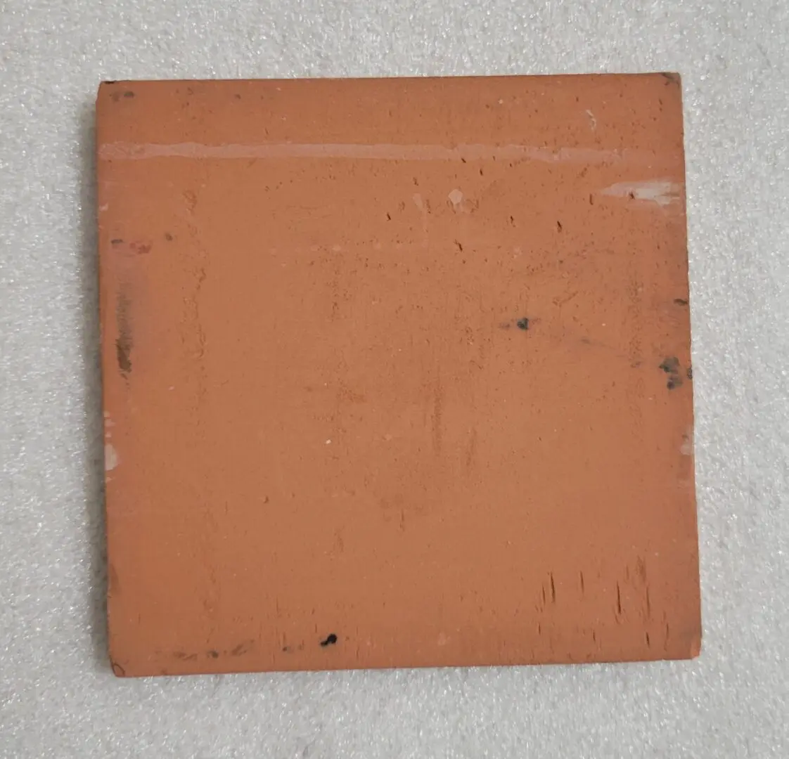 Worn terracotta square tile on white background