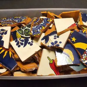 Colorful broken ceramic pieces with various designs in a box.