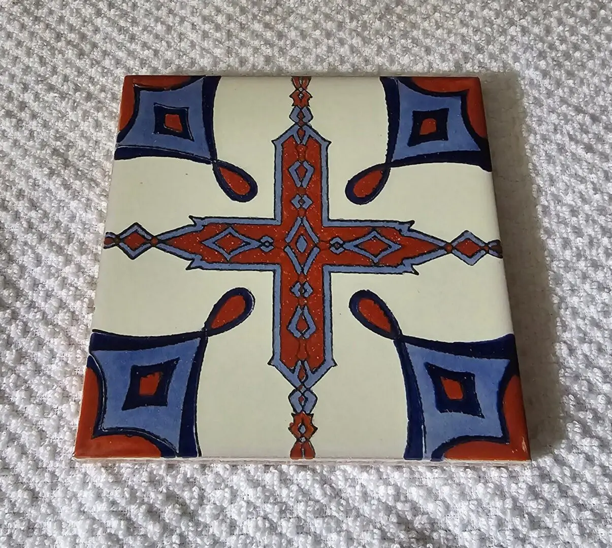 Decorative tile with geometric blue and red pattern.