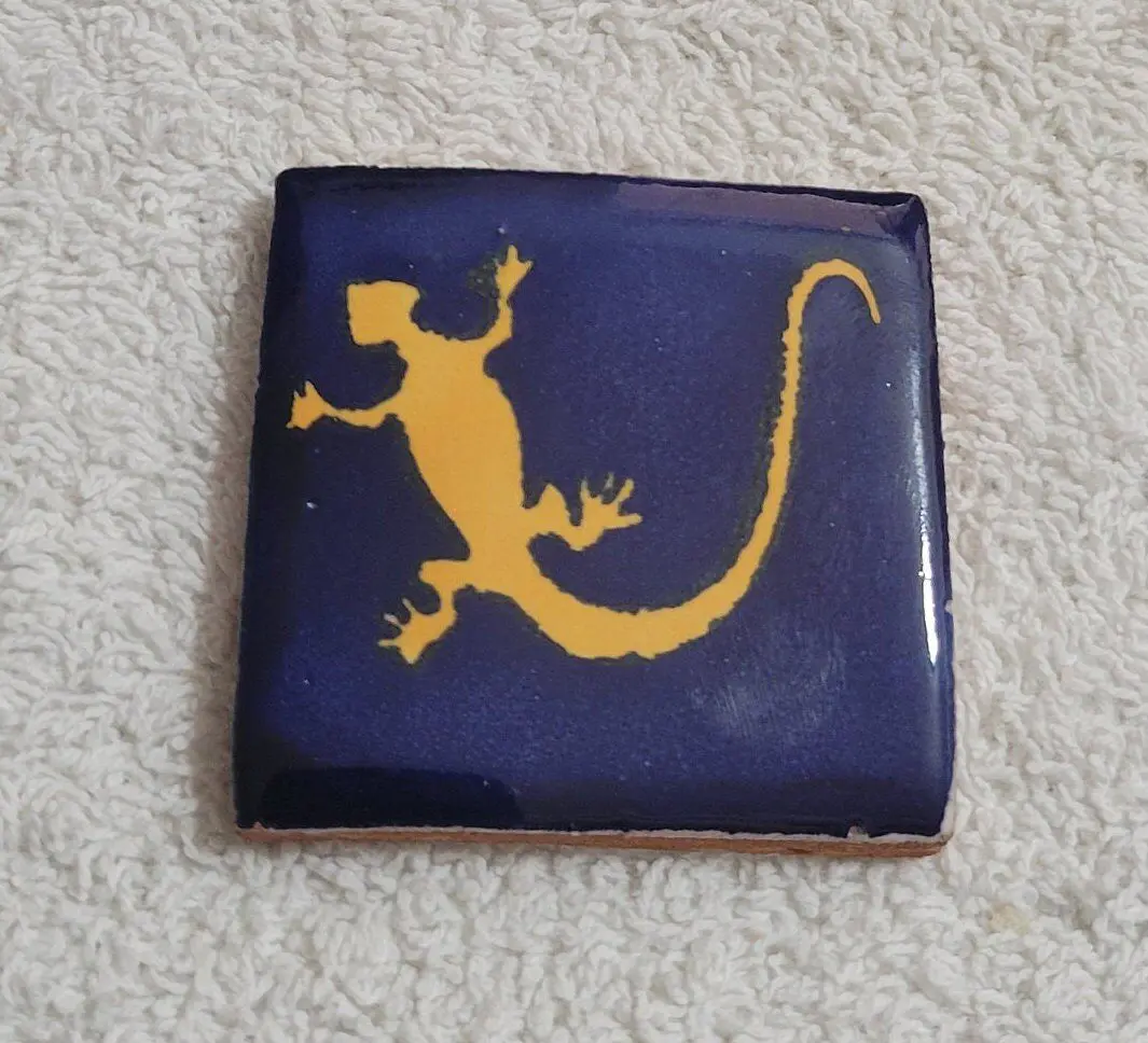 Tile with yellow lizard silhouette on blue.