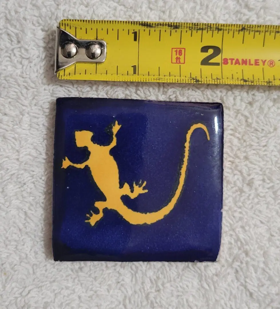 Yellow gecko tile beside measuring tape.