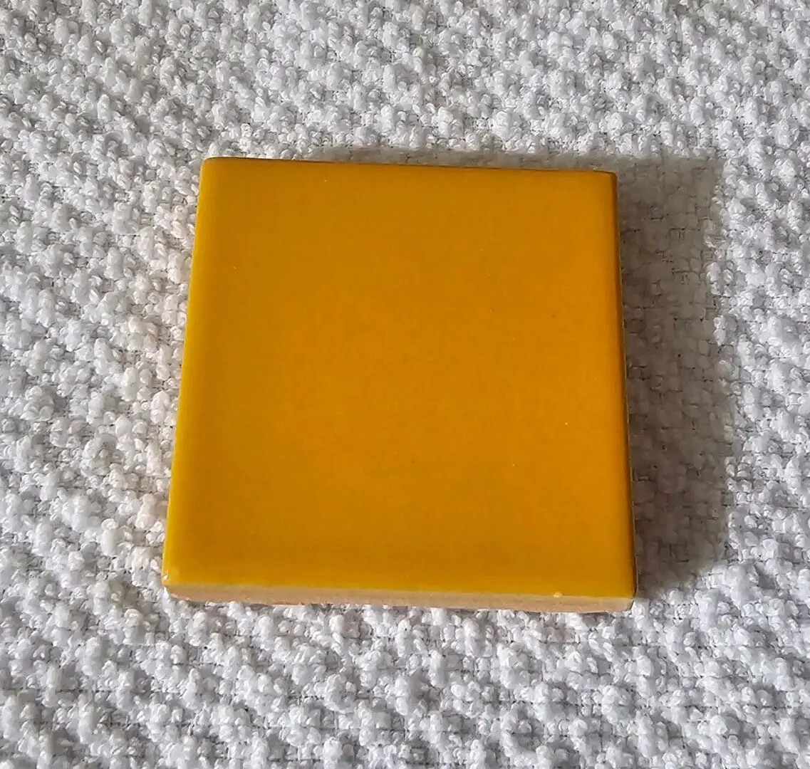 Glossy yellow square tile on white fabric
