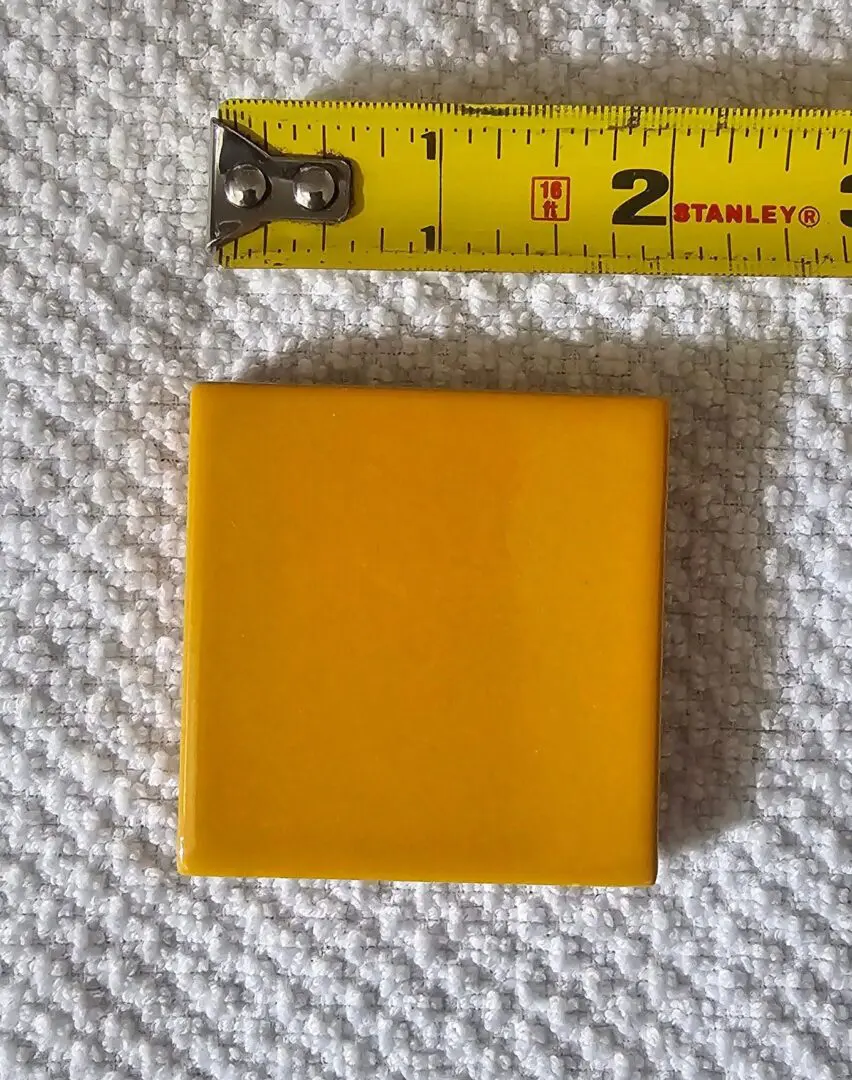 Yellow 2-inch square tile on textured fabric