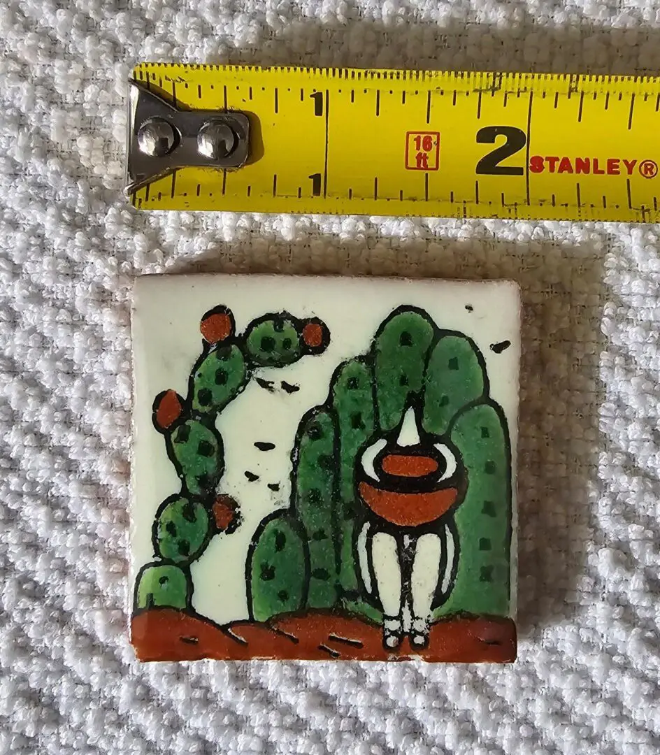 Tile art with cactus, measuring tape above.