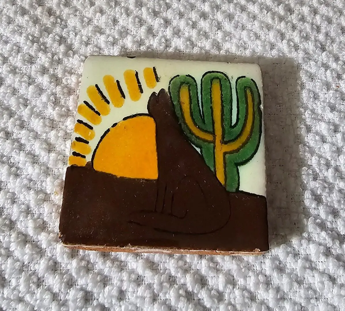 Sunset, cactus, and coyote design on tile.