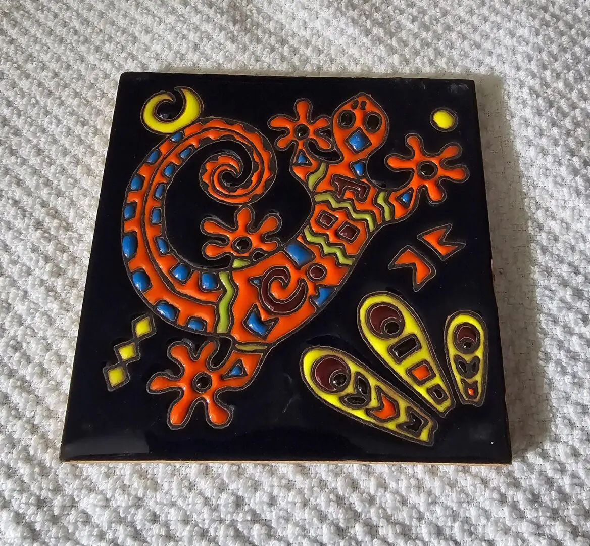 Colorful gecko design on decorative tile.