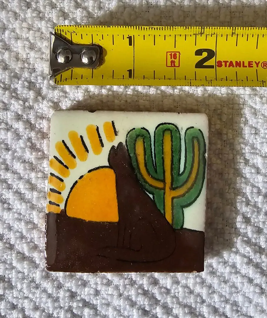 Tile with sun, cactus, and measuring tape.