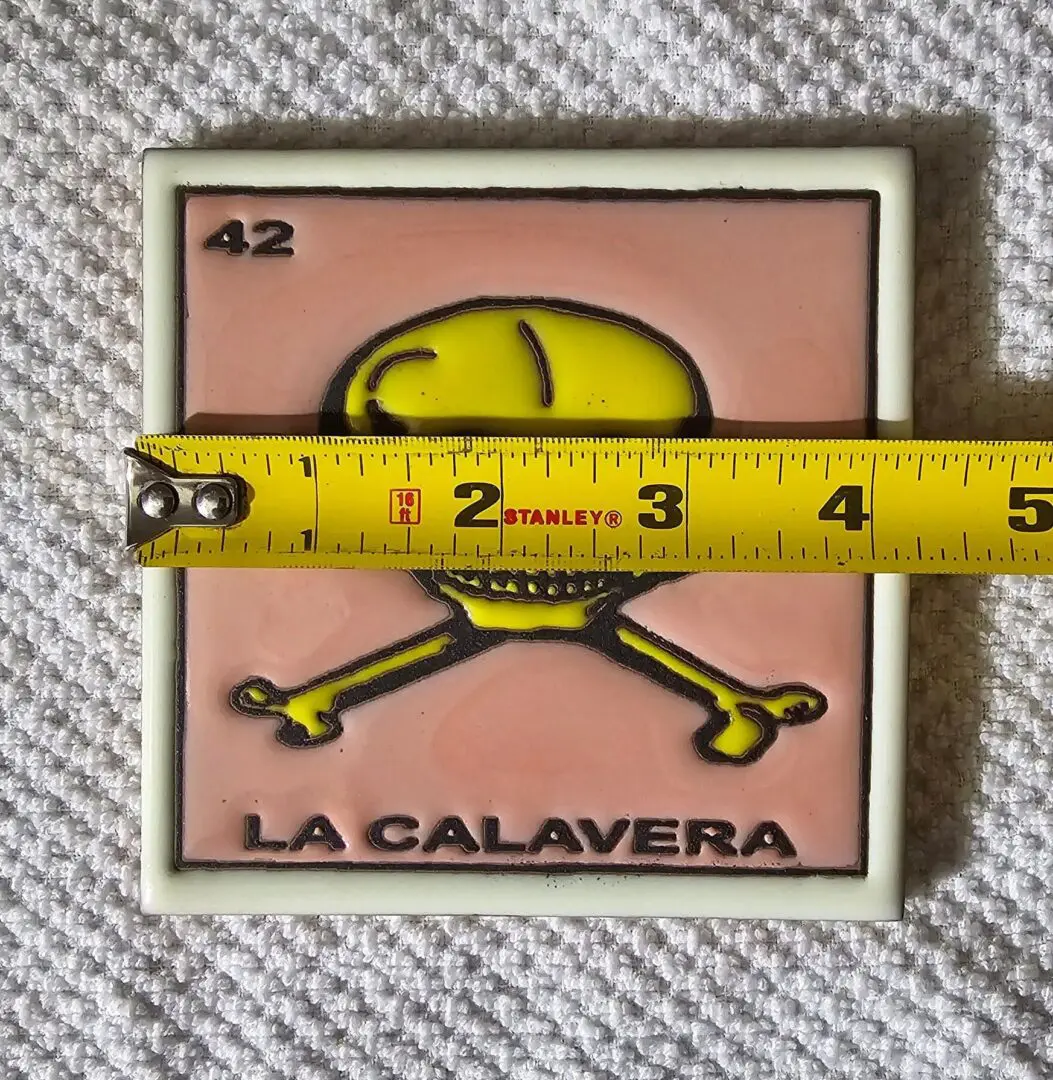 Tile with skull, crossbones, measuring tape.