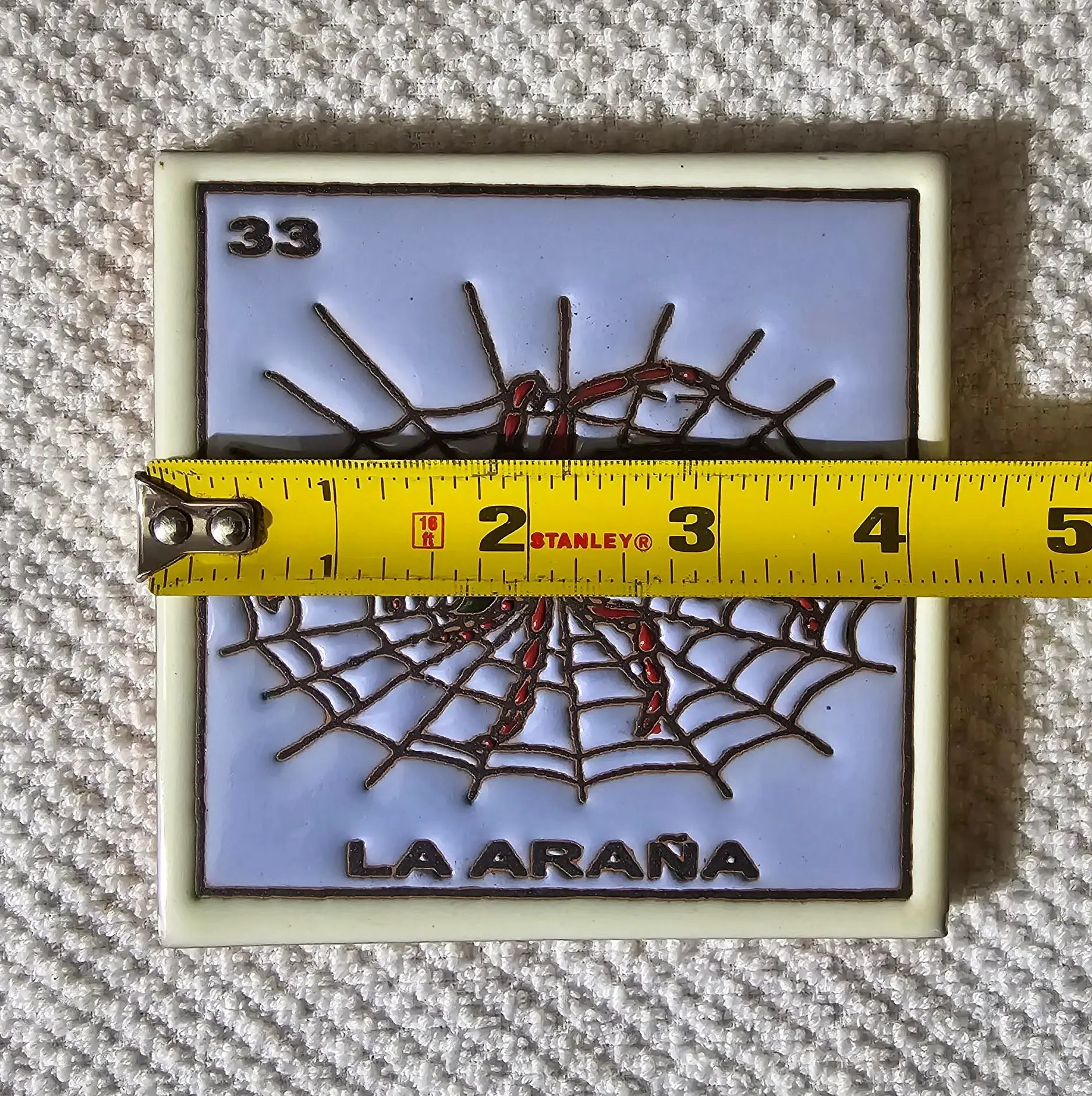 Tile with spider web and measuring tape.