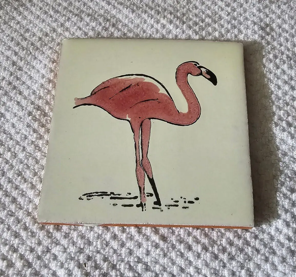 Tile with a painted flamingo design.