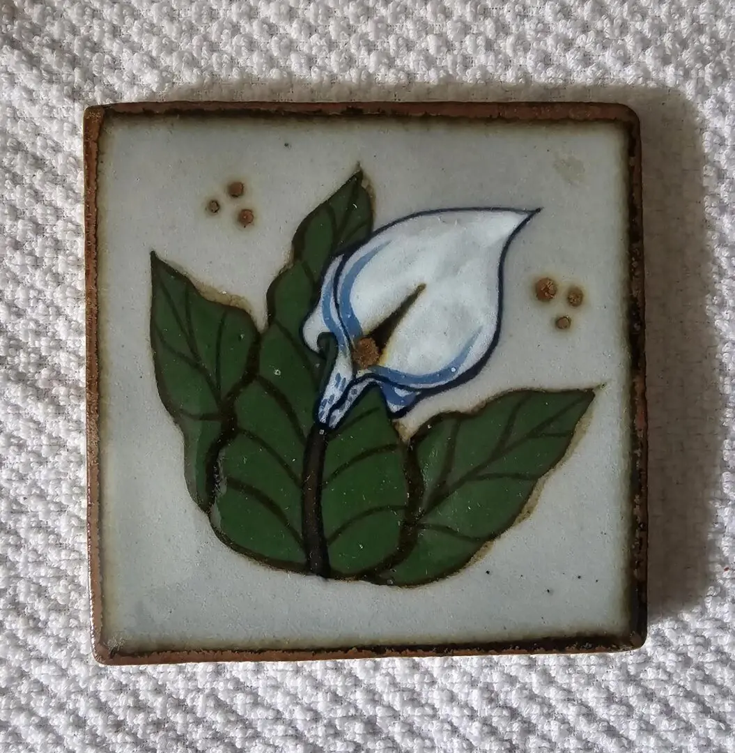 Ceramic tile with painted white flower.