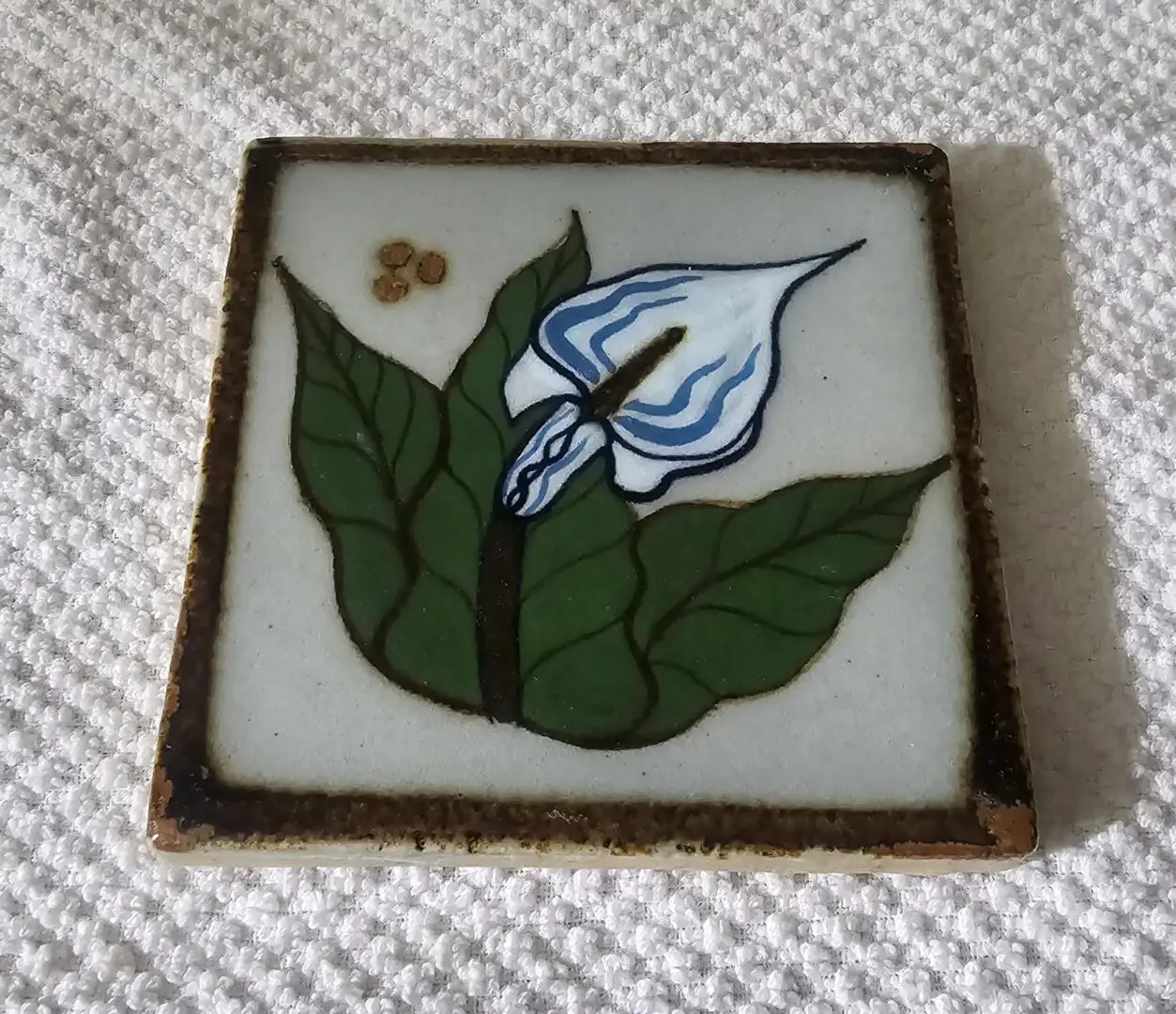 Ceramic tile with floral design and leaves.