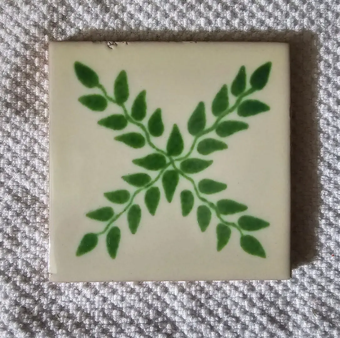Green leaf pattern on square ceramic tile.