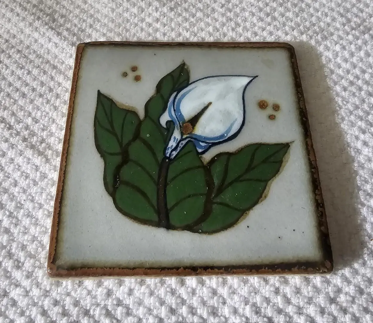Decorative tile with a flower and leaves.