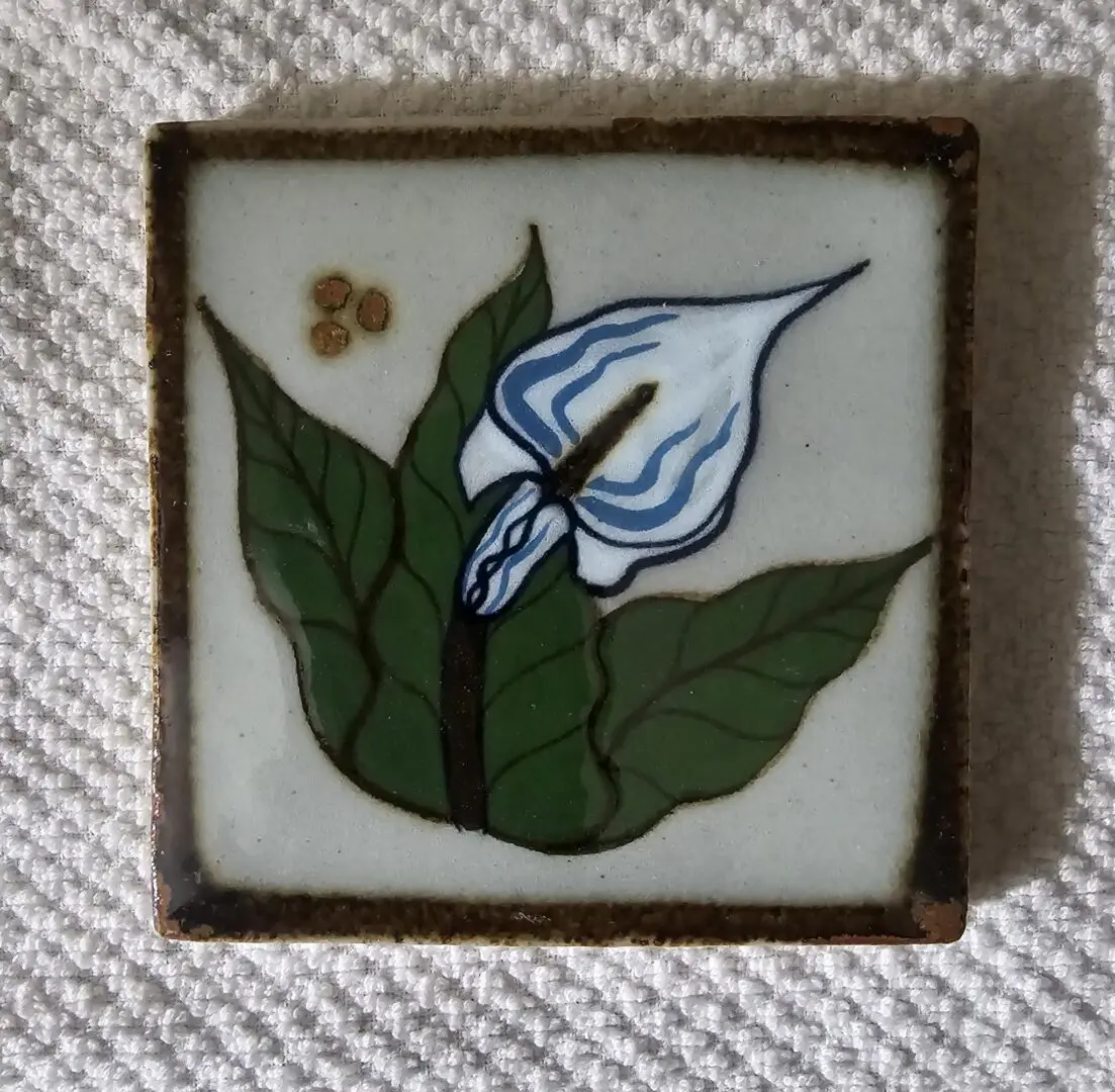 Ceramic tile with painted flower design.