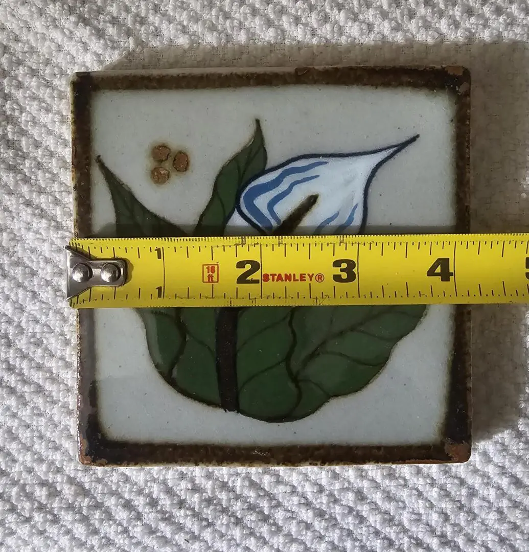 Tile with flower, measured by yellow tape.