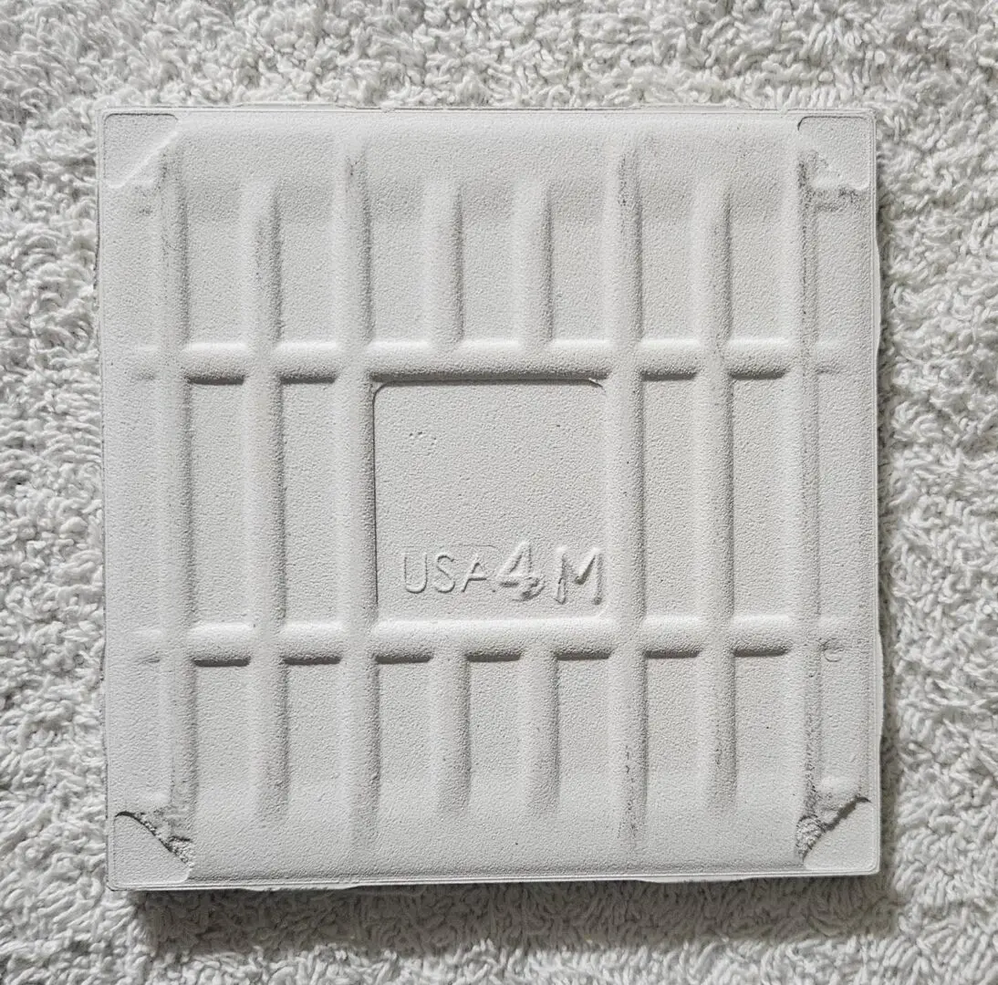White square tile with embossed grid pattern on textured surface.