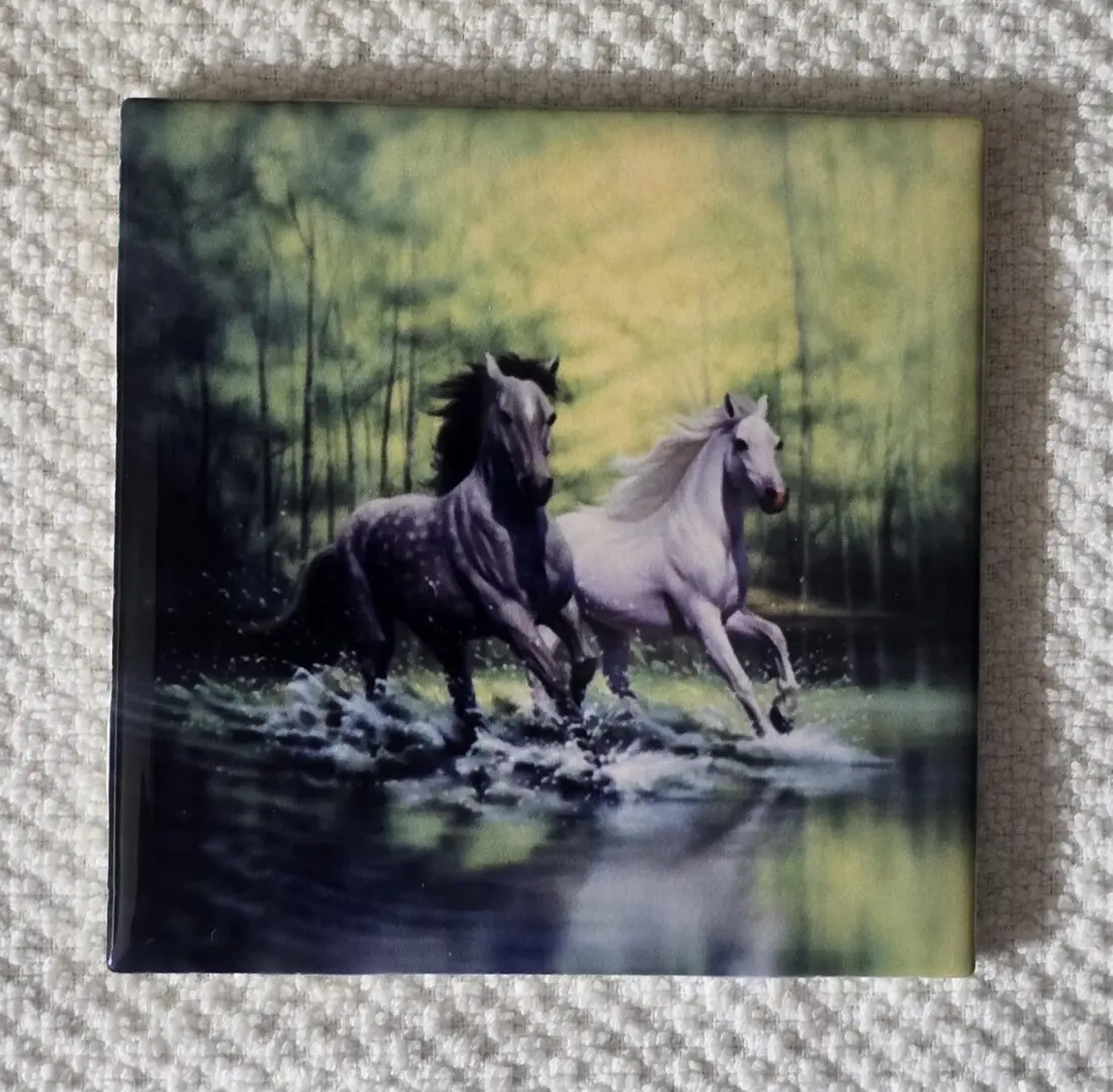 Two horses running through a forest stream.