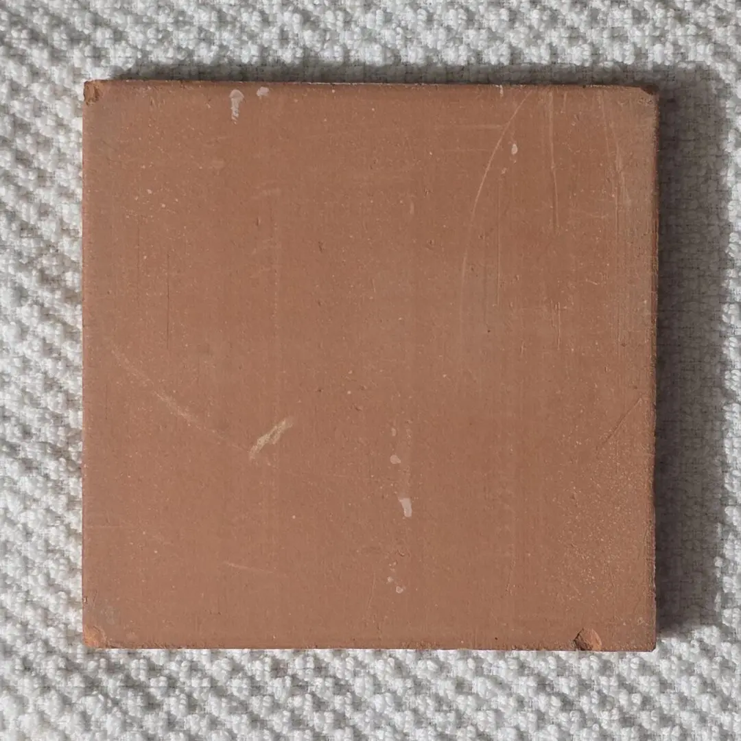 Square terracotta tile on textured fabric