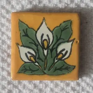 Decorative ceramic tile with white flowers and green leaves design.