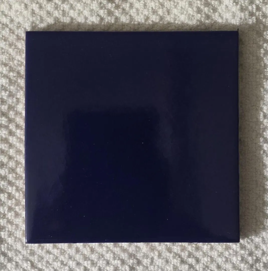 Glossy navy square tile on cream carpet