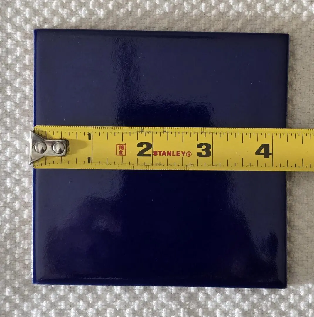 Square blue tile about 4 inches wide on a textured surface.
