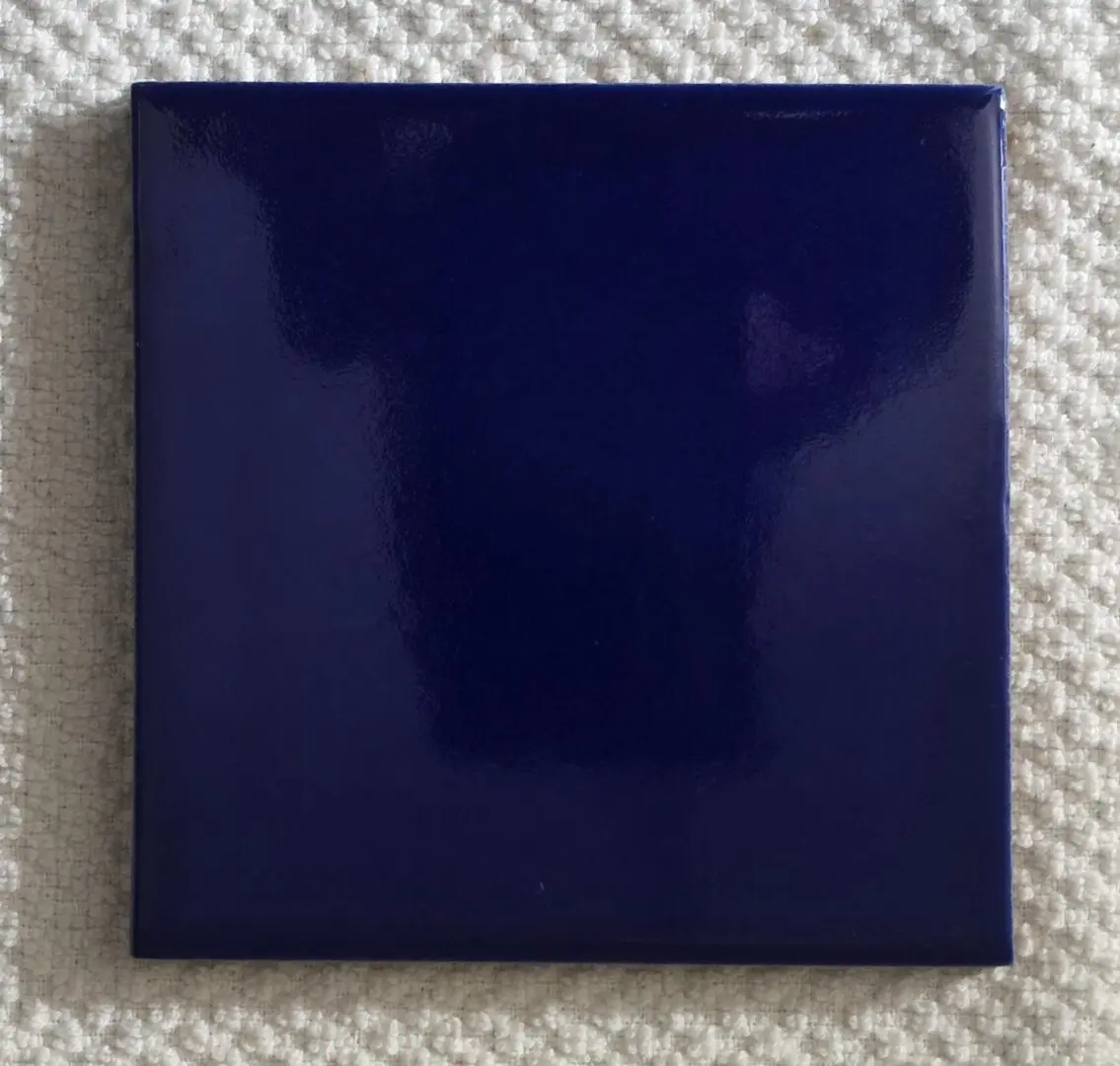 A glossy dark blue square tile with a reflective surface.