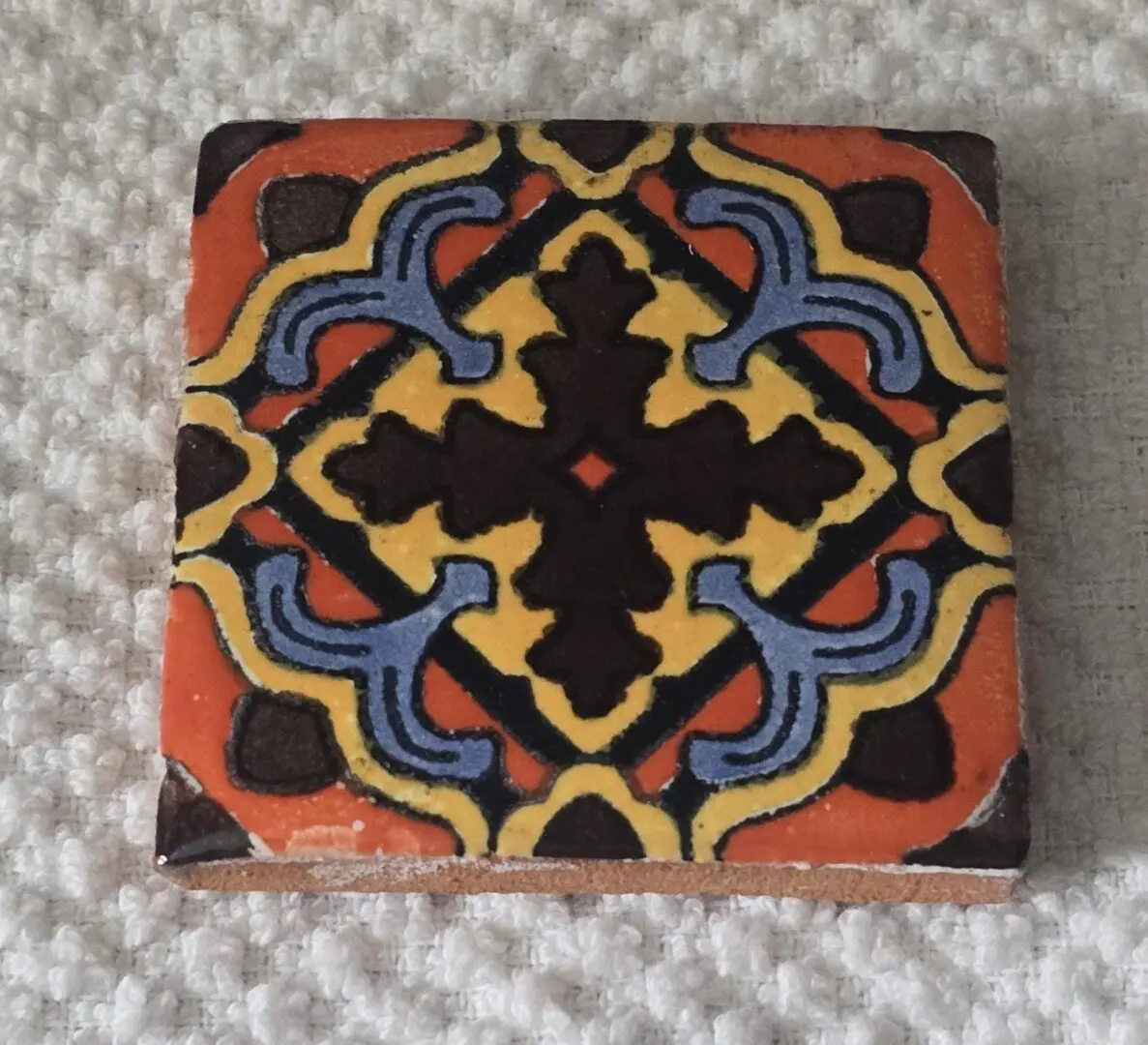 Colorful ceramic tile with intricate geometric pattern.