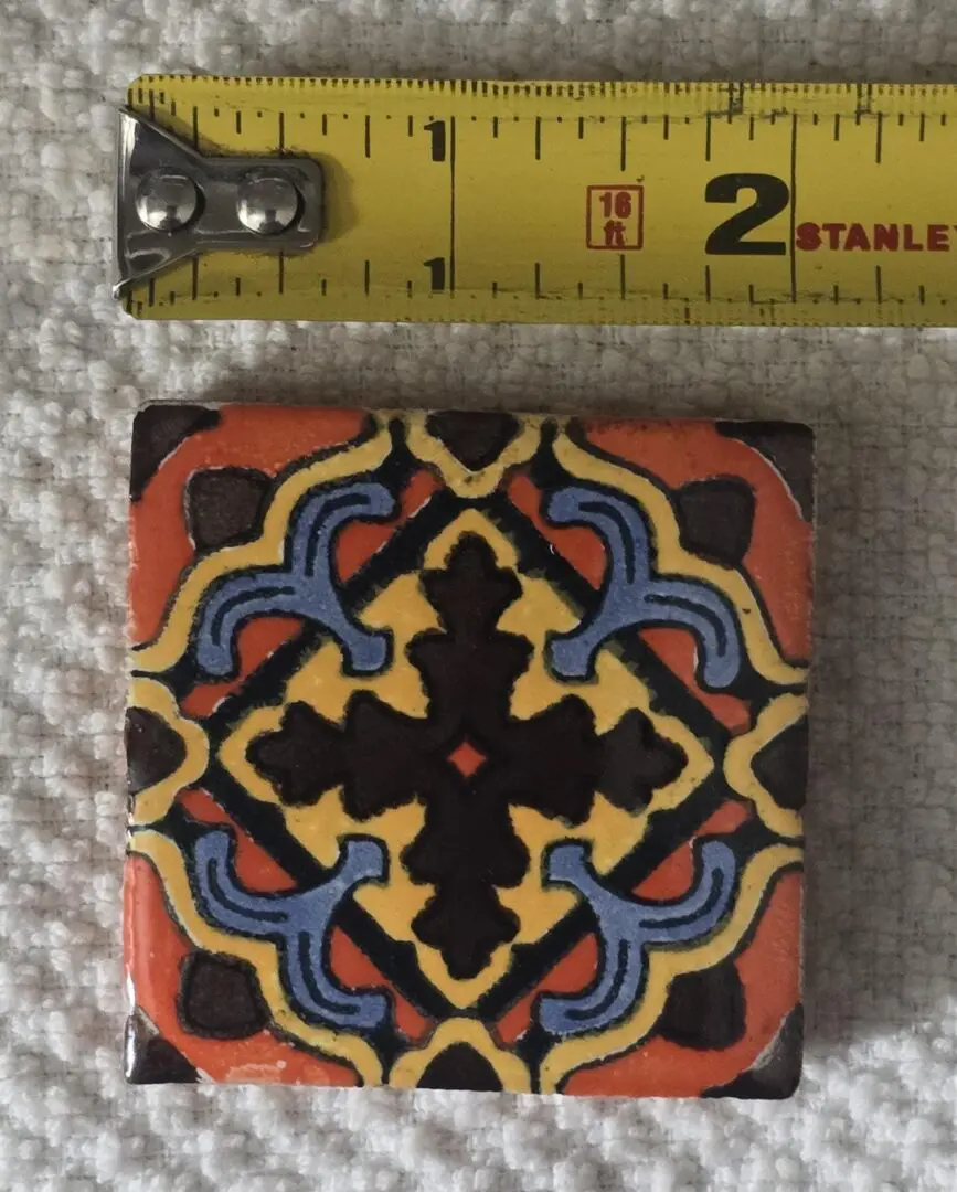 Colorful tile beside yellow measuring tape.