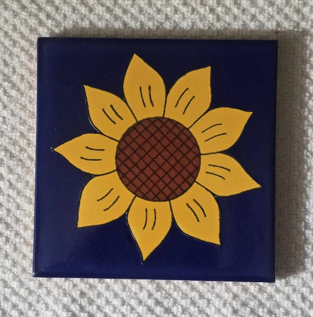 Tile with sunflower design on blue background.