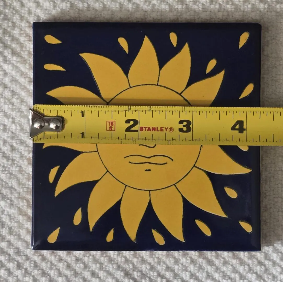 Tile with sun design and measuring tape.