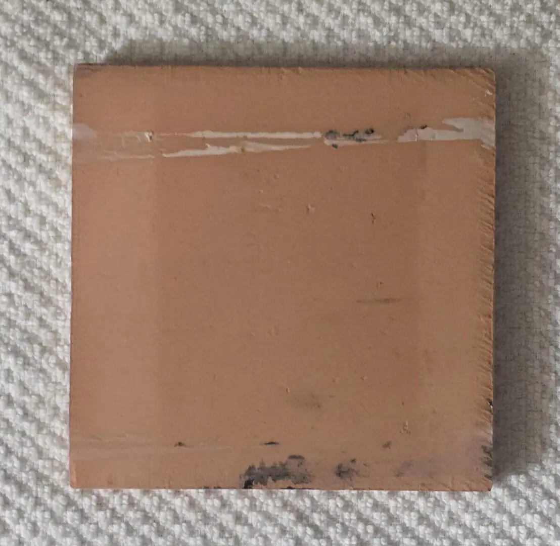 Peach ceramic tile sample on textured fabric