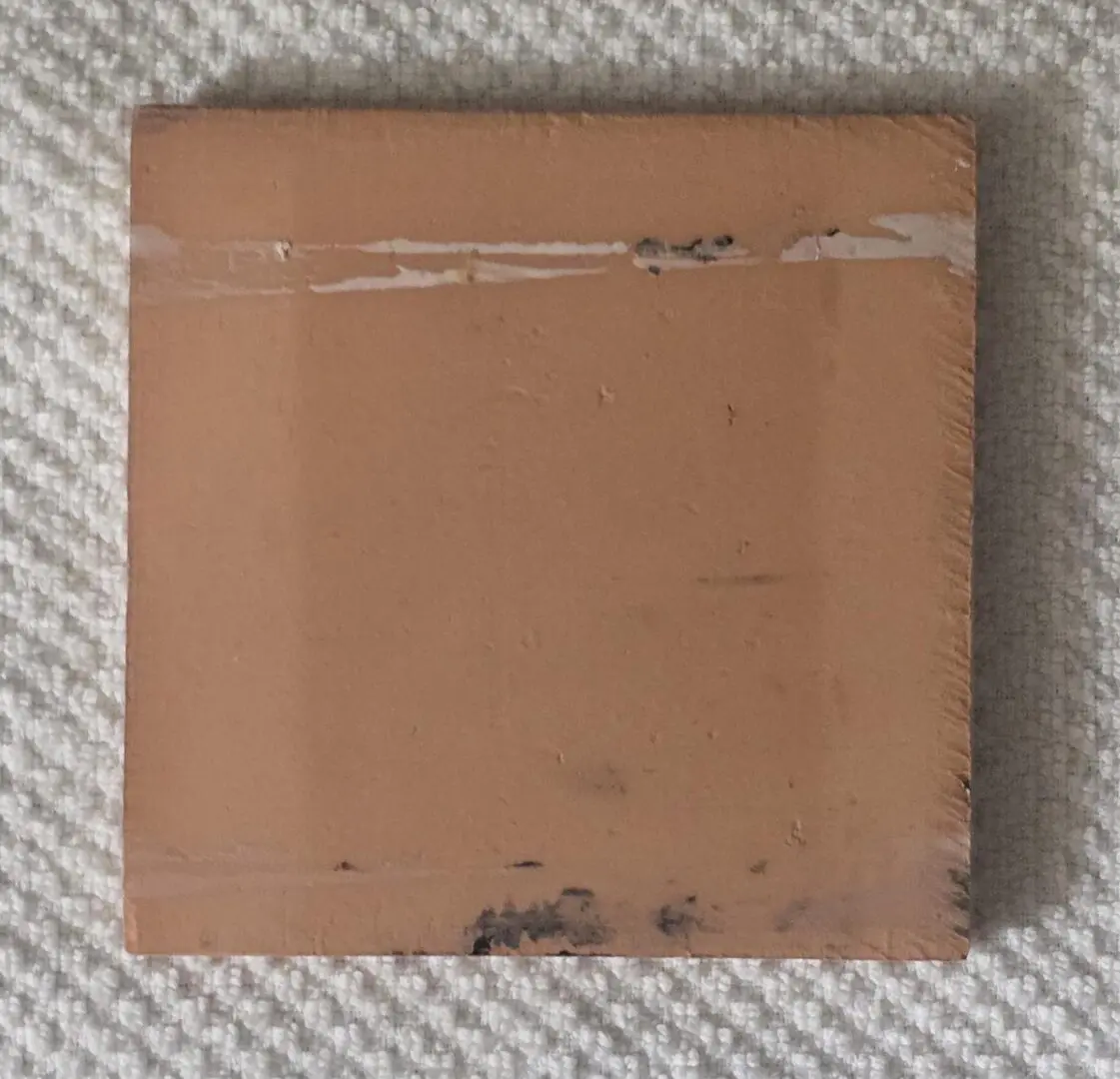 A plain, square piece of brown cardboard with some stains and tape marks.