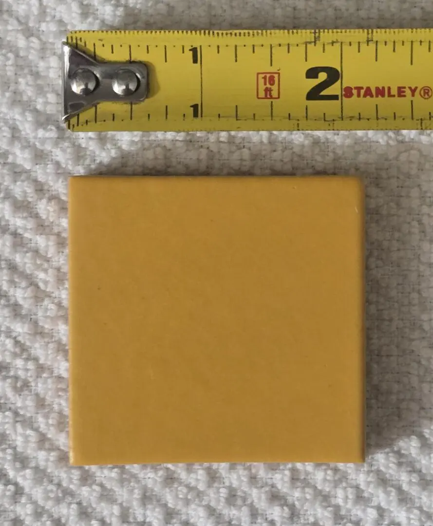 Yellow tile with measuring tape above.