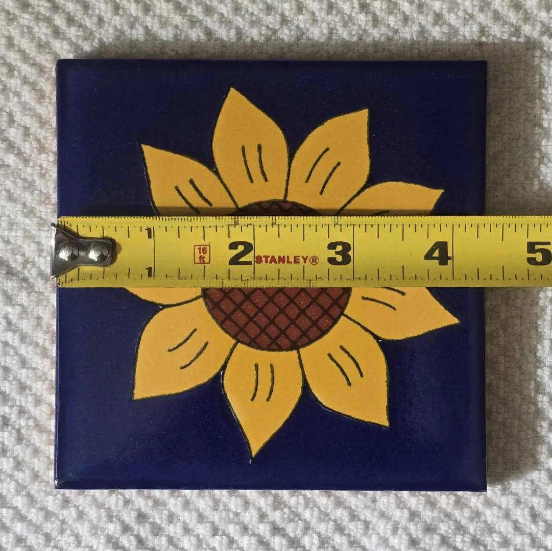 Sunflower tile with measuring tape on top.