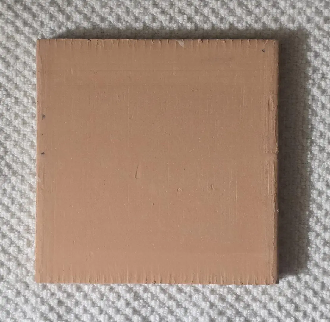 Brown square wooden panel on textured surface.