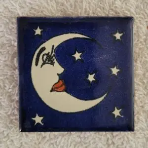 A crescent moon with a face surrounded by stars on a blue background.