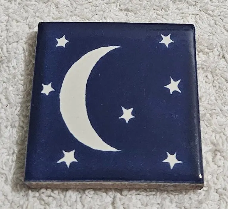 Blue tile with white crescent moon and stars design.