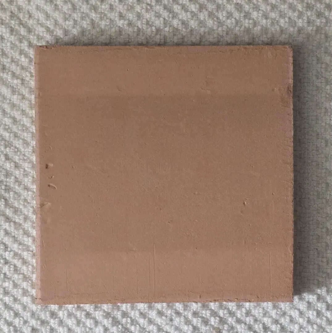 A plain, square cardboard box on a textured surface.