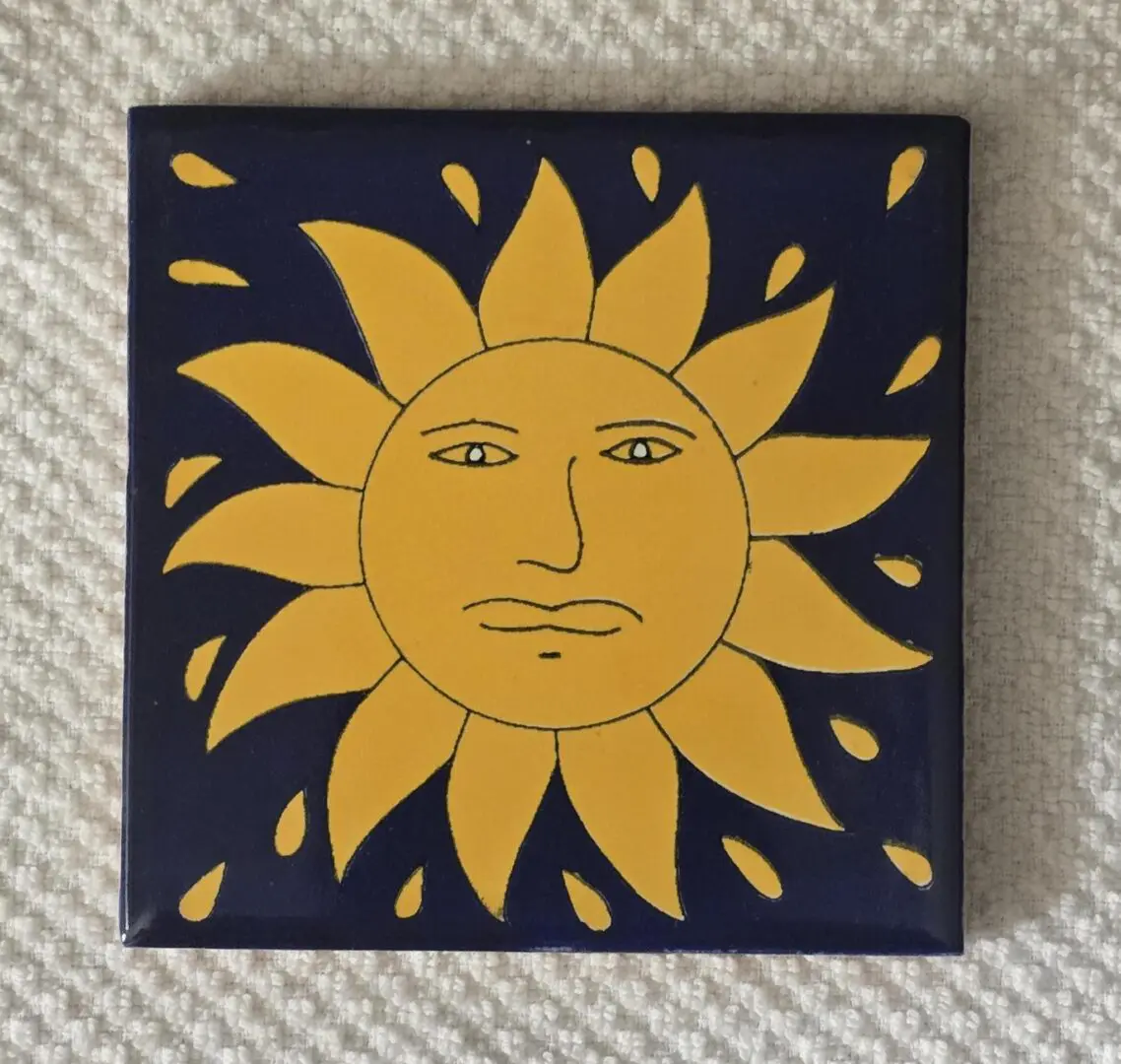 Yellow sun artwork on a blue tile.