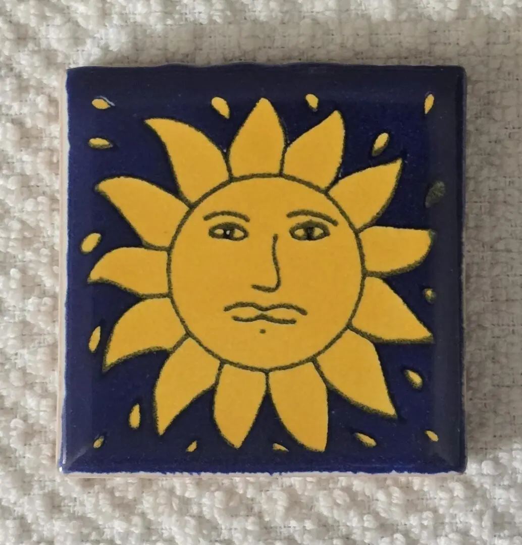 Yellow sun design on a ceramic tile.