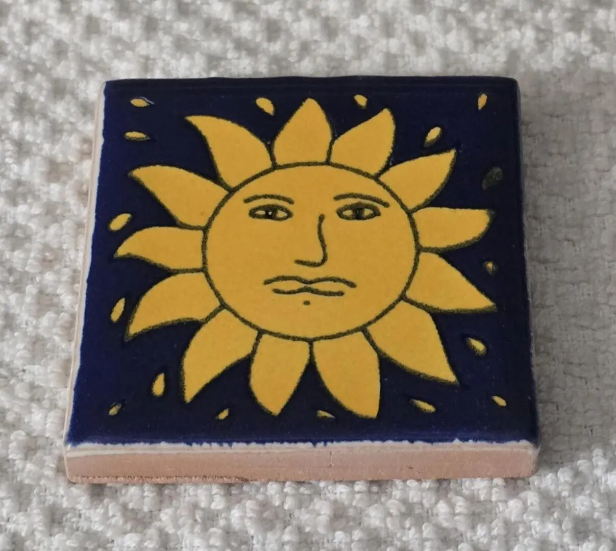Yellow sun design on square ceramic tile.
