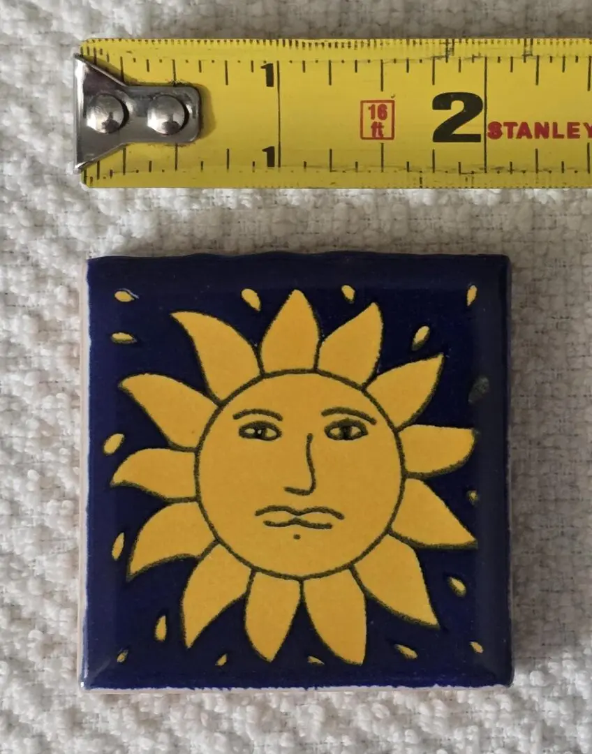 Tile with sun design beside measuring tape.