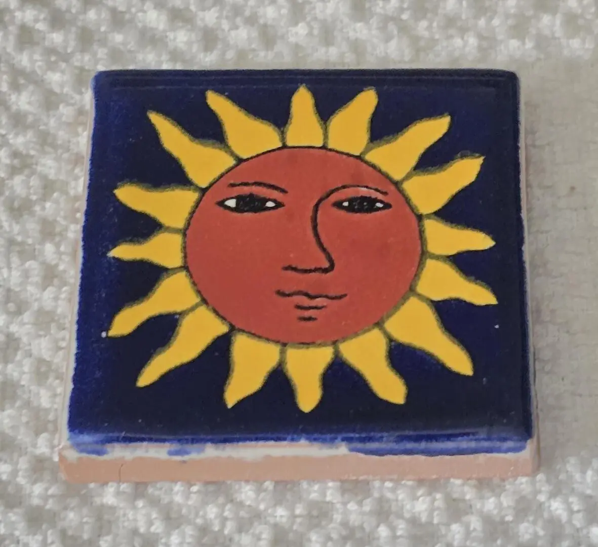 Colorful tile with sun face design.
